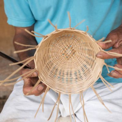Close-up of a craftsman weaving a wicker basket, showcasing intricate details.