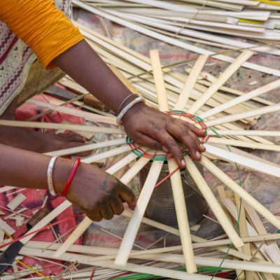Rural woman hands in close up view weaving a basket from bamboo cane strands at a handicraft fare at Kolkata